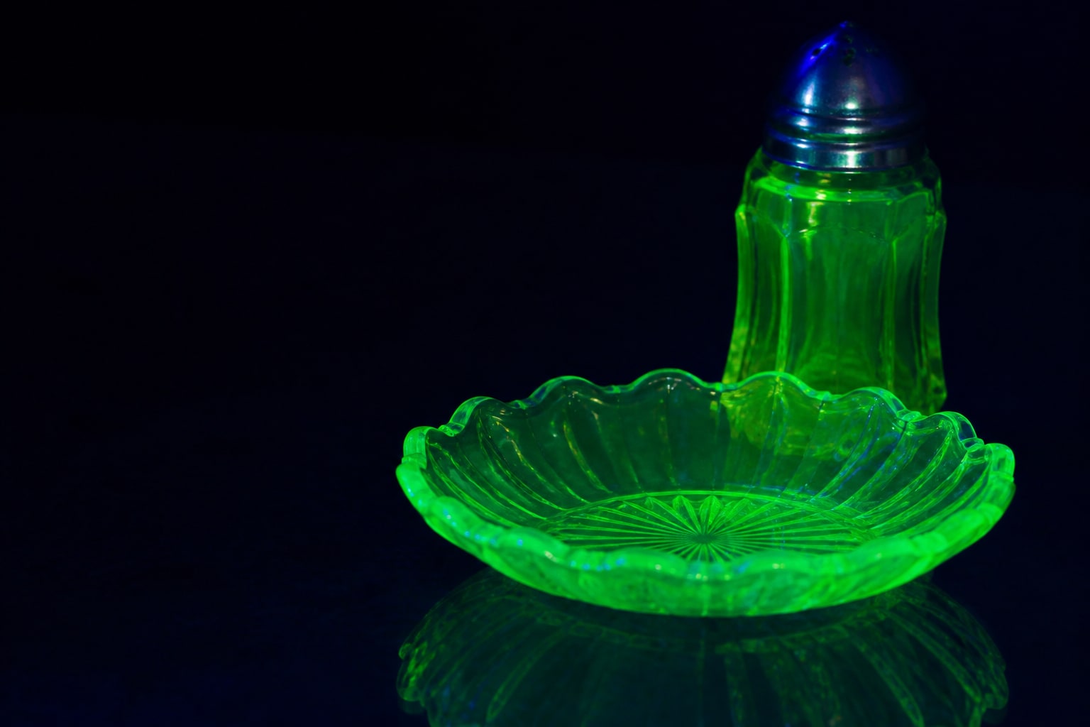 Uranium-glass objects fluorescing bright green under ultraviolet light